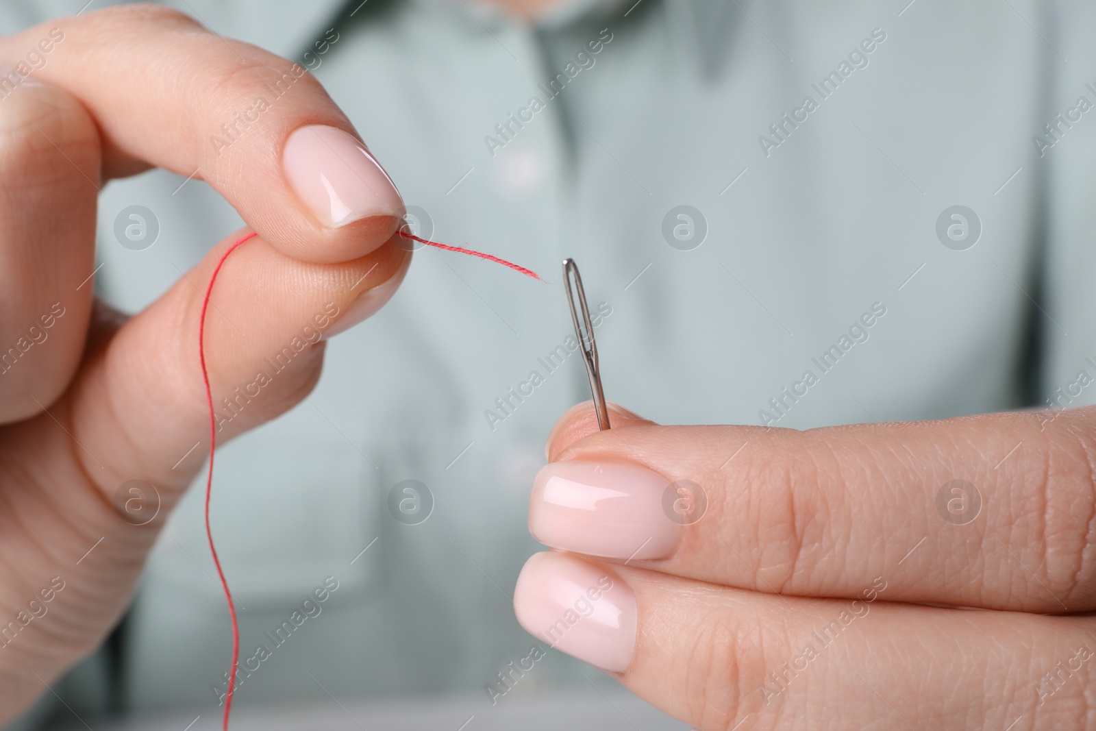 Photo of Woman threading needle, closeup view. Sewing equipment