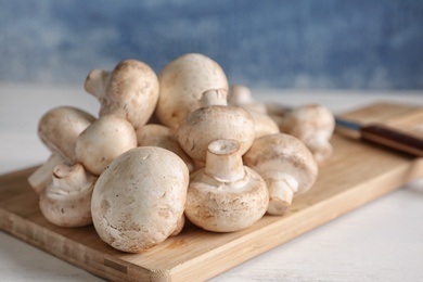 Photo of Fresh champignon mushrooms on wooden board, closeup