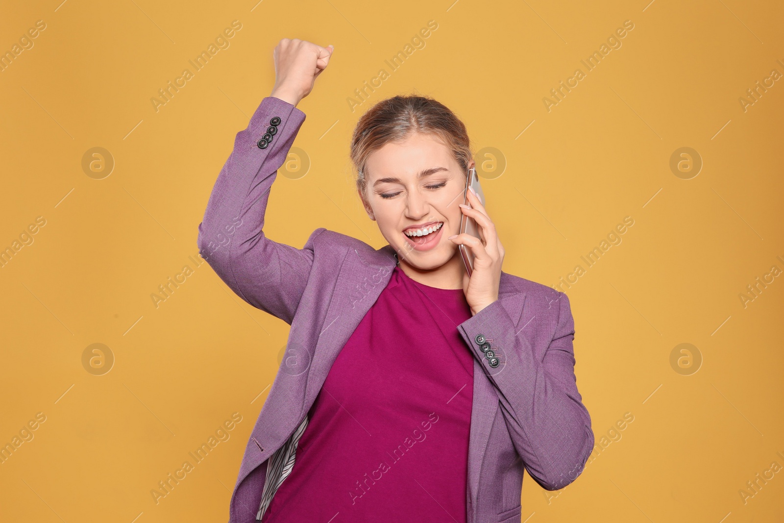 Photo of Happy young businesswoman with smartphone celebrating victory on color background