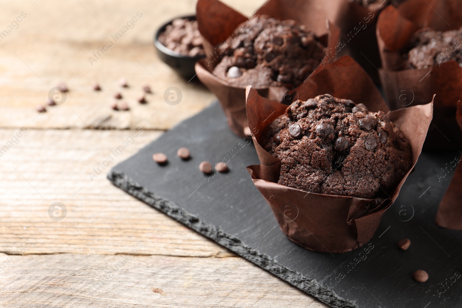 Photo of Delicious chocolate muffins on wooden table, closeup. Space for text