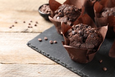 Delicious chocolate muffins on wooden table, closeup. Space for text