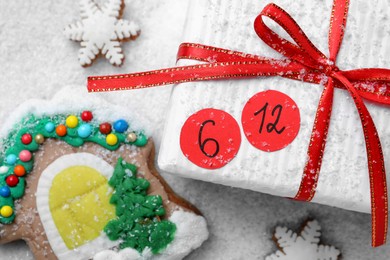 Photo of Saint Nicholas Day. Wrapped gift box with date December 6 and gingerbread cookies on snow, flat lay