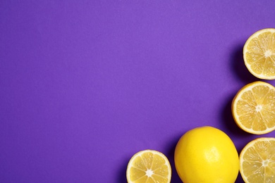 Photo of Whole and cut lemons on purple background, flat lay. Space for text