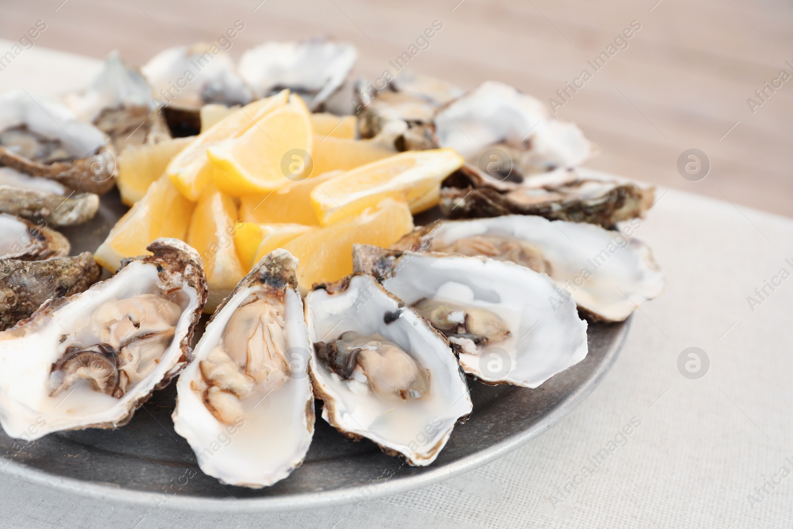 Photo of Fresh oysters with cut juicy lemon on plate, closeup