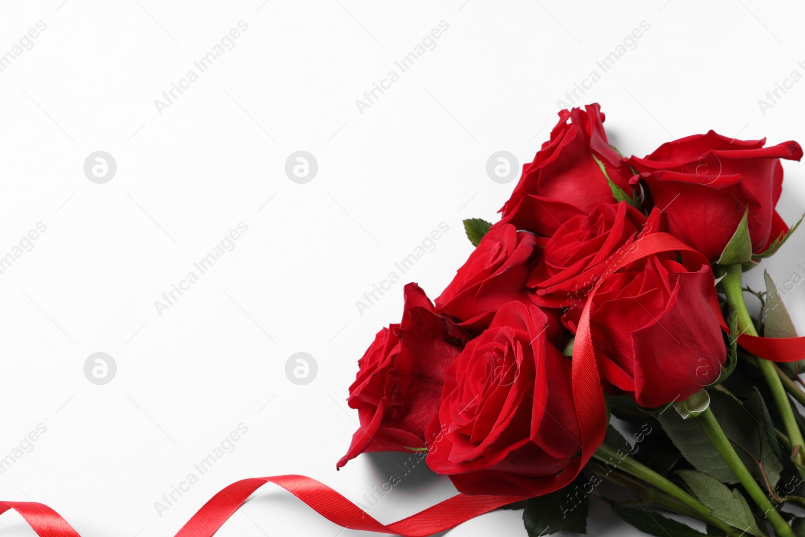 Photo of Beautiful red roses and ribbon on white background, top view. Space for text