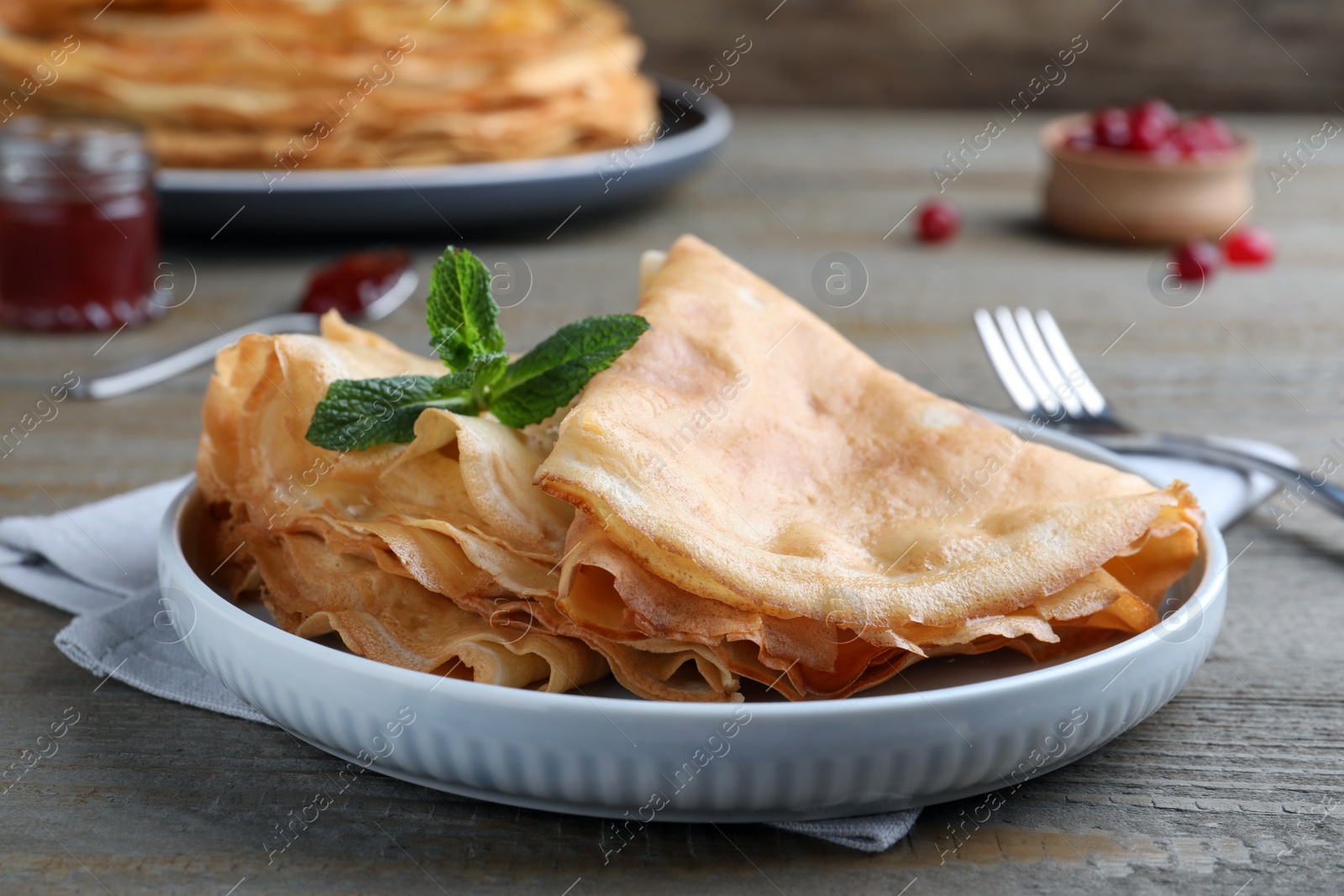 Photo of Delicious crepes served with mint on grey wooden table, closeup