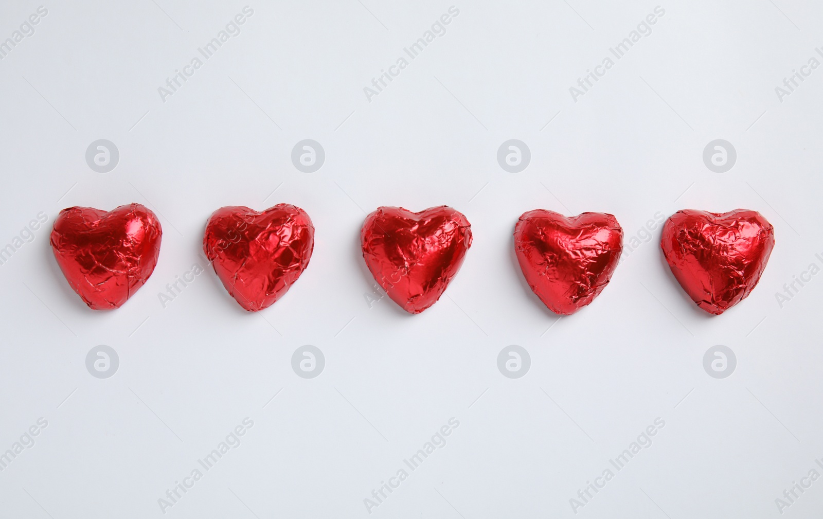 Photo of Heart shaped chocolate candies on white background, flat lay. Valentine's day treat