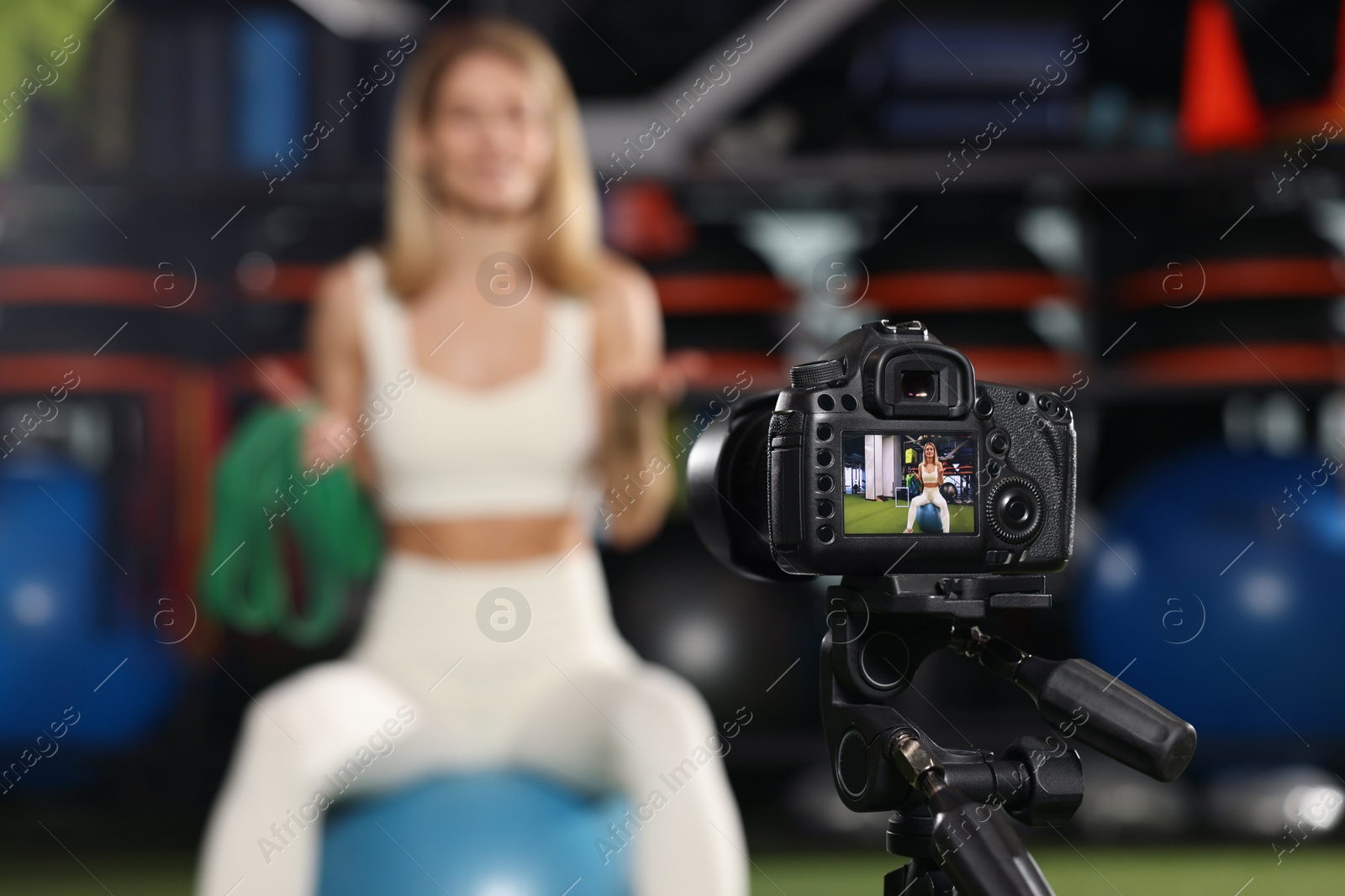 Photo of Fitness trainer recording online classes in gym, focus on camera. Space for text