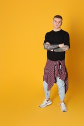 Photo of Young man with tattoos on yellow background. Space for text