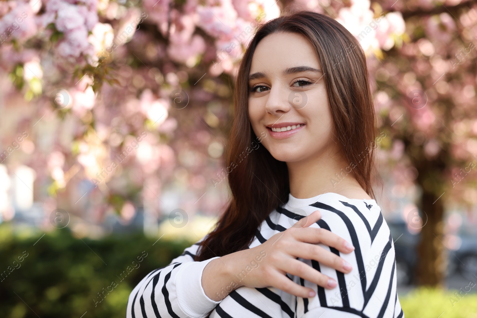 Photo of Beautiful woman near blossoming tree on spring day, space for text