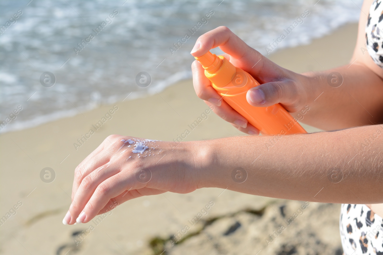 Photo of Woman applying sun protection cream on her hand at beach, closeup