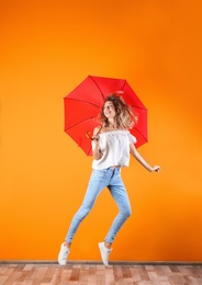 Woman with red umbrella near color wall