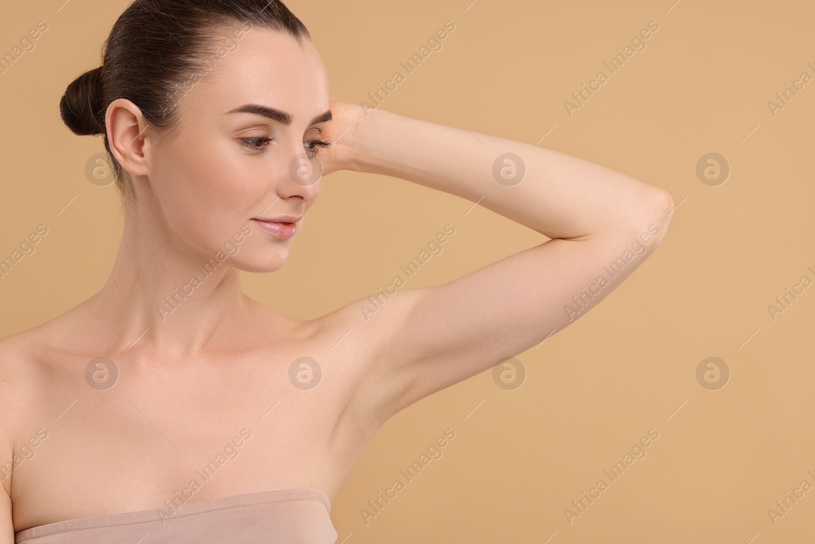 Photo of Beautiful woman showing armpit with smooth clean skin on beige background