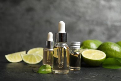 Photo of Lime essential oil and cut citrus fruits on black table