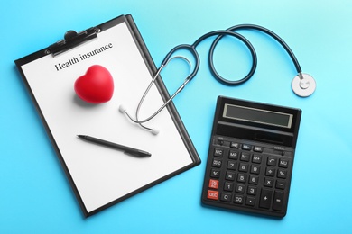 Photo of Flat lay composition with medical insurance form, calculator and stethoscope on blue background