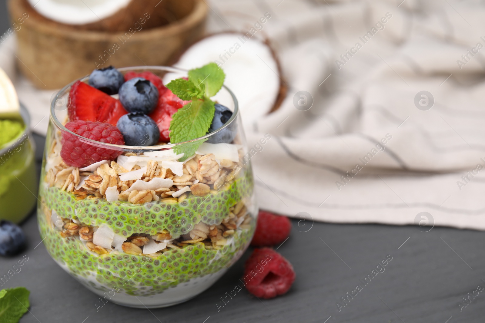 Photo of Tasty oatmeal with chia matcha pudding and berries on black wooden table, closeup. Space for text. Healthy breakfast