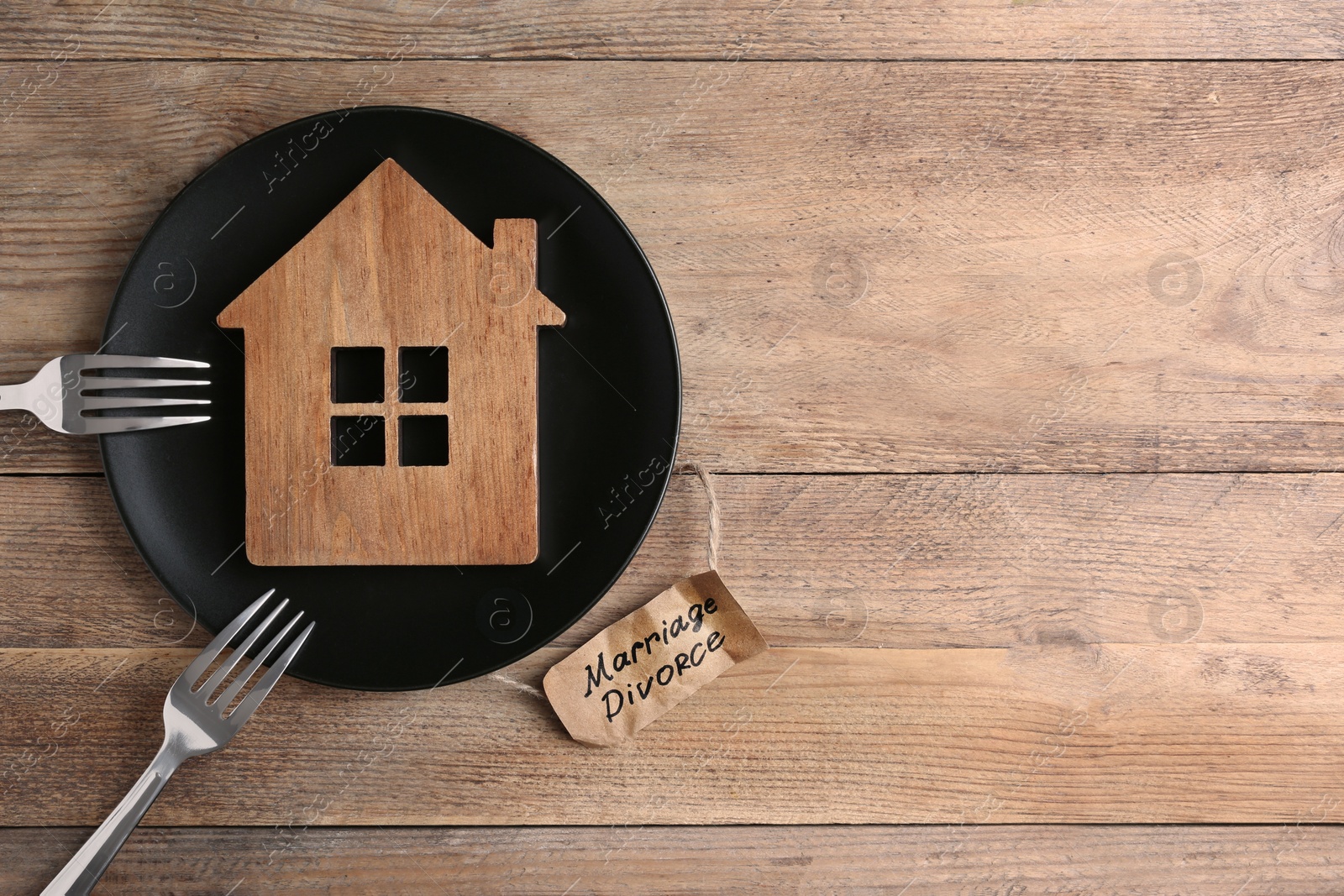 Photo of Divorce concept. Plate with model of house and forks near paper card on wooden table, flat lay. Space for text