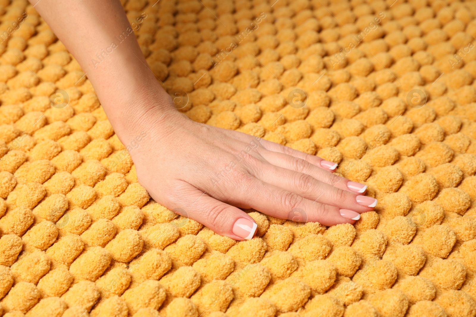 Photo of Woman touching soft yellow fabric, closeup view