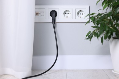 Power sockets and electric plug on grey wall