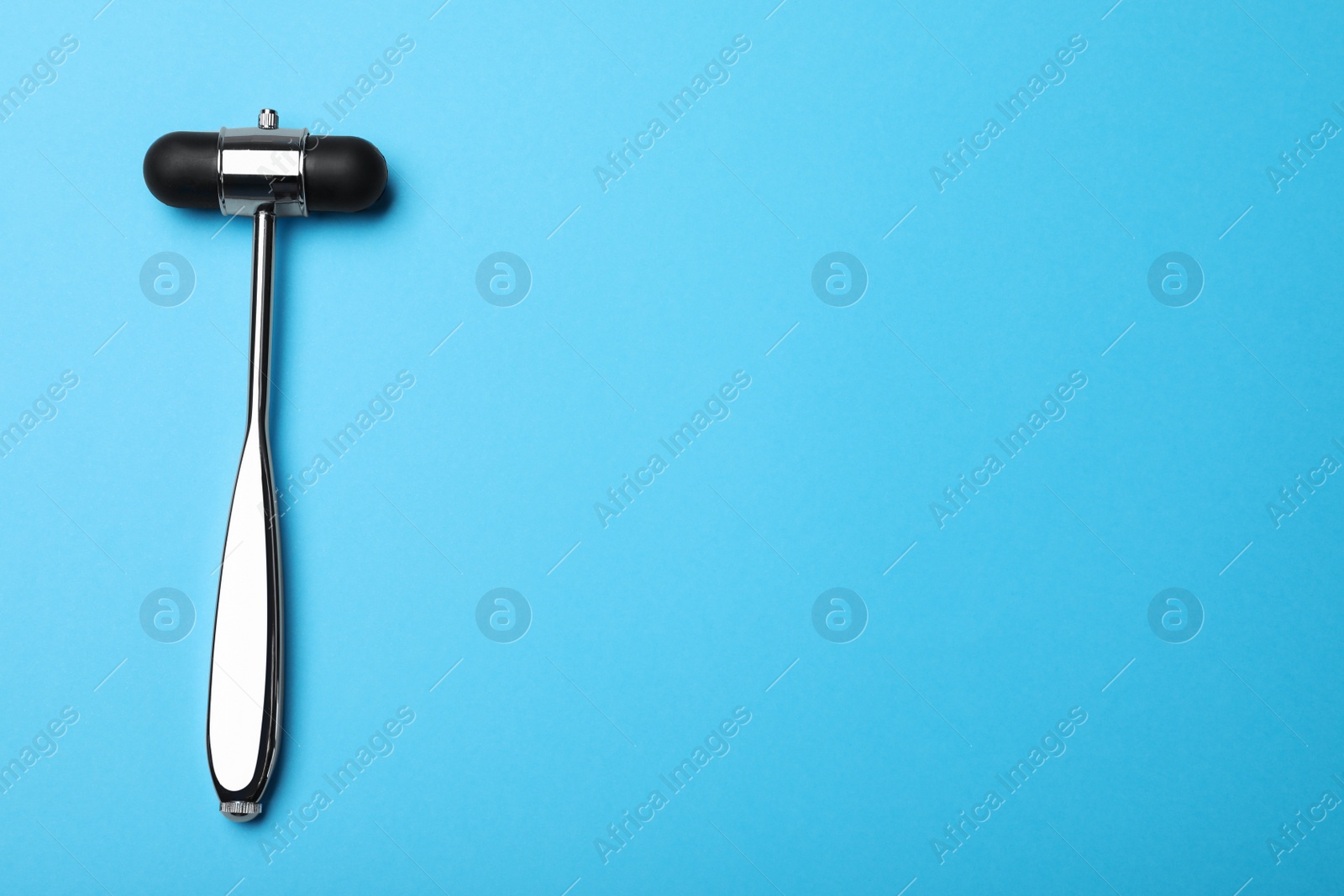 Photo of Reflex hammer on light blue background, top view with space for text. Nervous system diagnostic