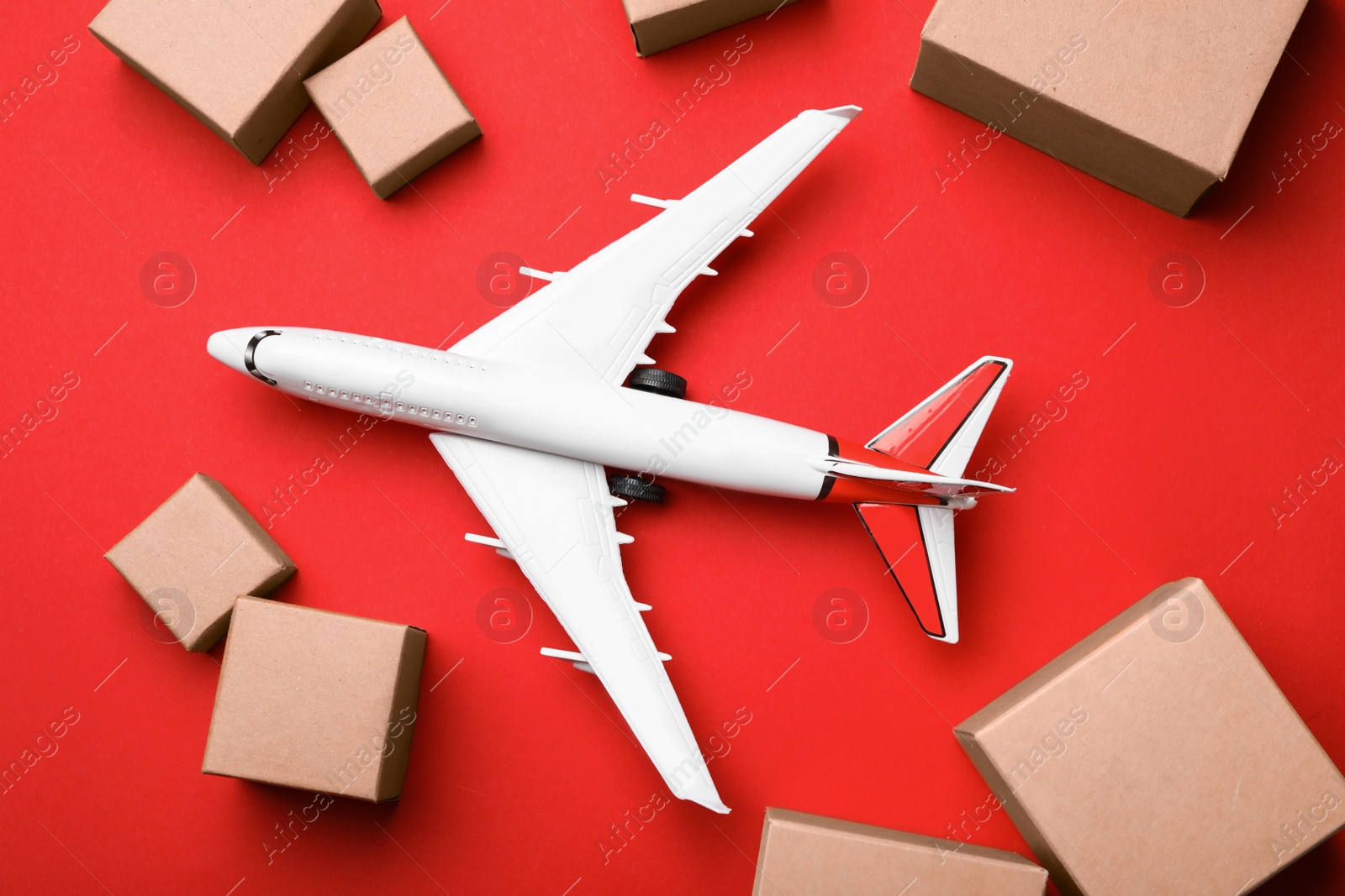 Photo of Top view of toy plane with boxes on red background. Logistics and wholesale concept