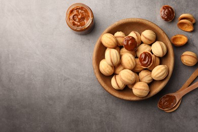 Delicious nut shaped cookies with boiled condensed milk on gray textured table, flat lay. Space for text