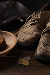 Photo of Poverty. Old shoes, bag, piece of bread and coins on wooden table