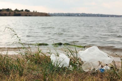 Photo of Plastic garbage scattered on grass near river
