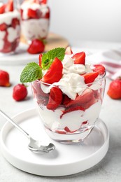 Photo of Delicious strawberries with whipped cream served on light grey table