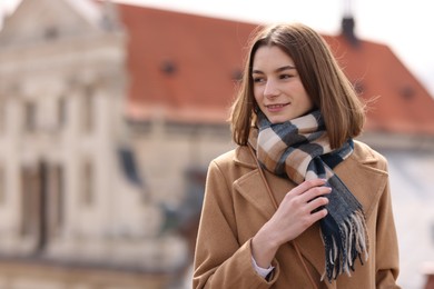 Beautiful woman in warm scarf outdoors, space for text