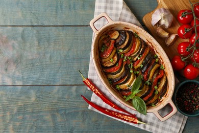 Delicious ratatouille and ingredients on wooden table, flat lay. Space for text