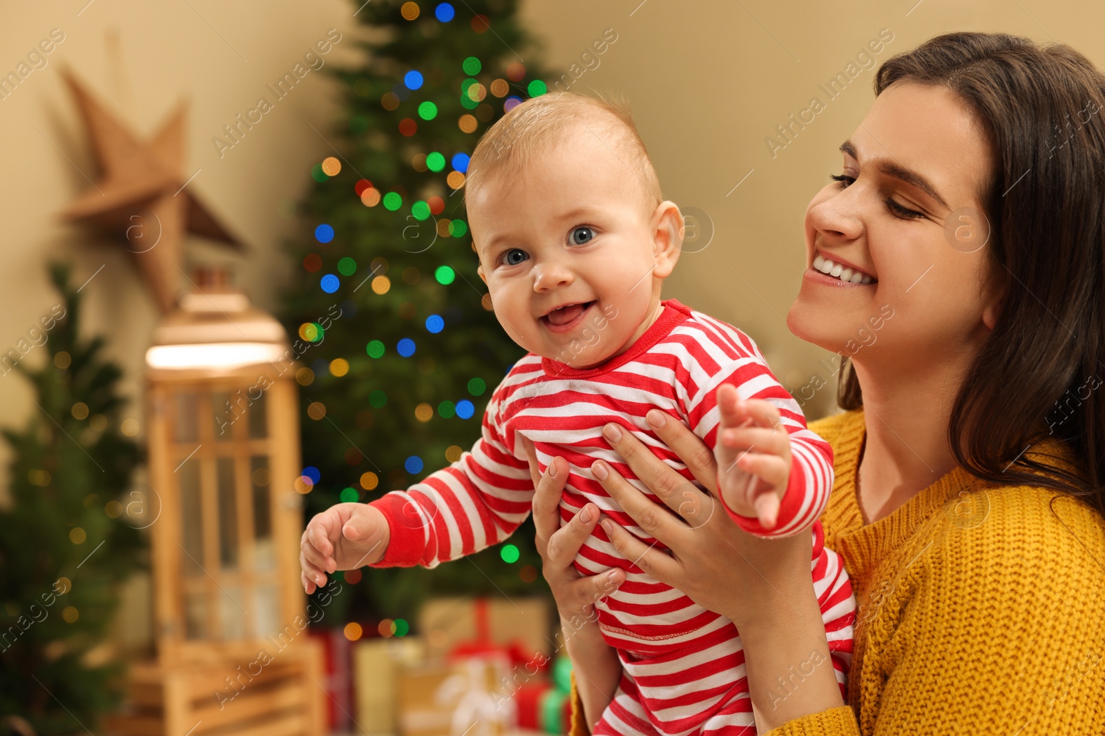 Photo of Happy young mother with her cute baby in room decorated for Christmas. Winter holiday