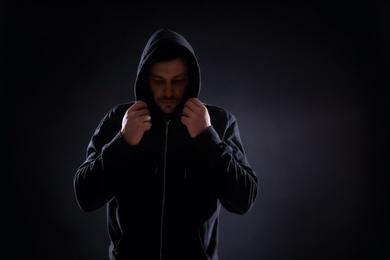 Photo of Mysterious man in hoodie on dark background. Dangerous criminal