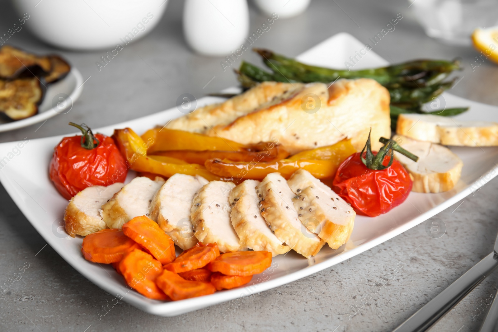 Photo of Tasty cooked chicken fillet and vegetables served on grey table. Healthy meals from air fryer