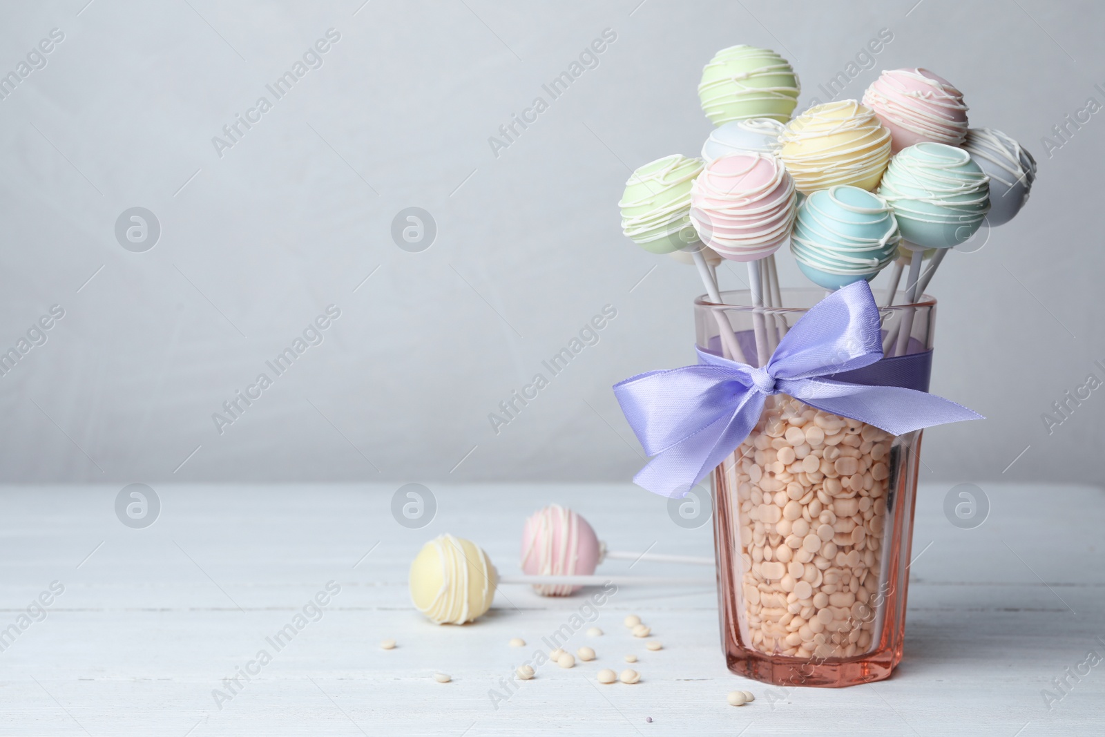 Photo of Sweet cake pops on white wooden table against grey background. Space for text