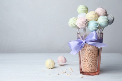 Photo of Sweet cake pops on white wooden table against grey background. Space for text