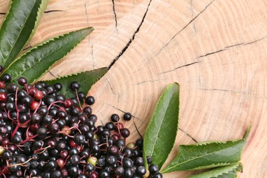 Photo of Pile of tasty elderberries (Sambucus) and leaves on wooden stump, top view. Space for text