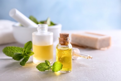 Bottles with mint essential oil on table