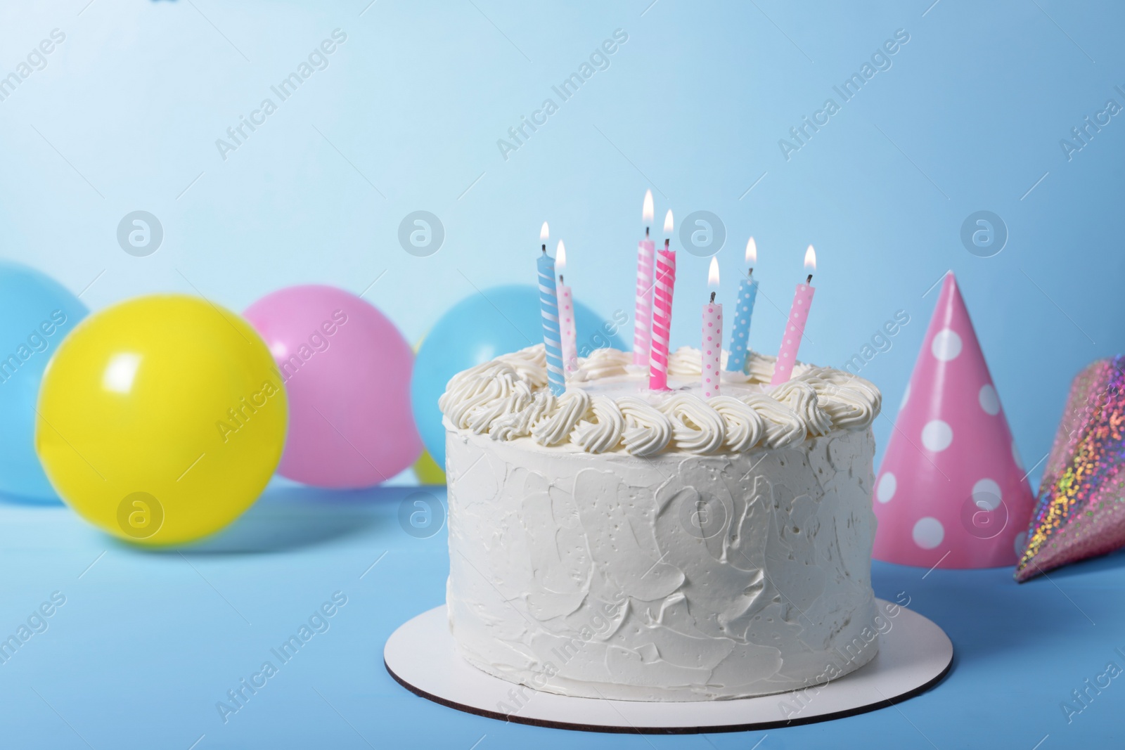 Photo of Delicious cake with burning candles and festive decor on light blue background. Space for text