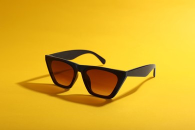 Photo of Stylish pair of sunglasses on yellow background