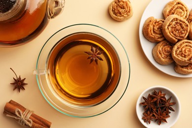 Photo of Flat lay composition with aromatic tea, cookies and anise stars on beige table