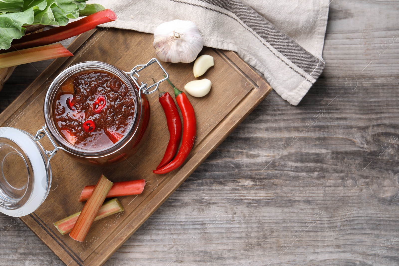 Photo of Tasty rhubarb sauce and ingredients on wooden table, flat lay. Space for text