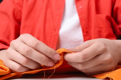 Photo of Woman sewing cloth with needle at table, closeup