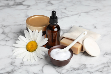 Photo of Composition with chamomile flower and cosmetic products on white marble table