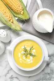 Photo of Delicious creamy corn soup served on white marble table, flat lay