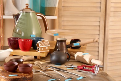 Photo of Many different cooking utensils on wooden table indoors. Garage sale