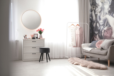 Stylish room interior with dressing table, mirror, sofa and floral wallpaper