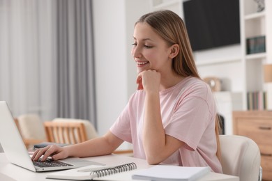 Online learning. Teenage girl typing on laptop at table