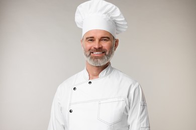 Photo of Happy chef in uniform on grey background