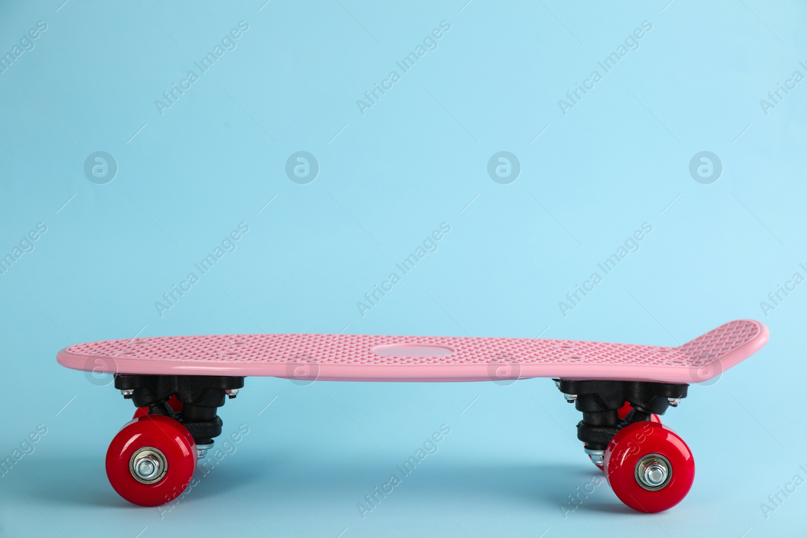 Photo of Pink skateboard on light blue background. Space for text